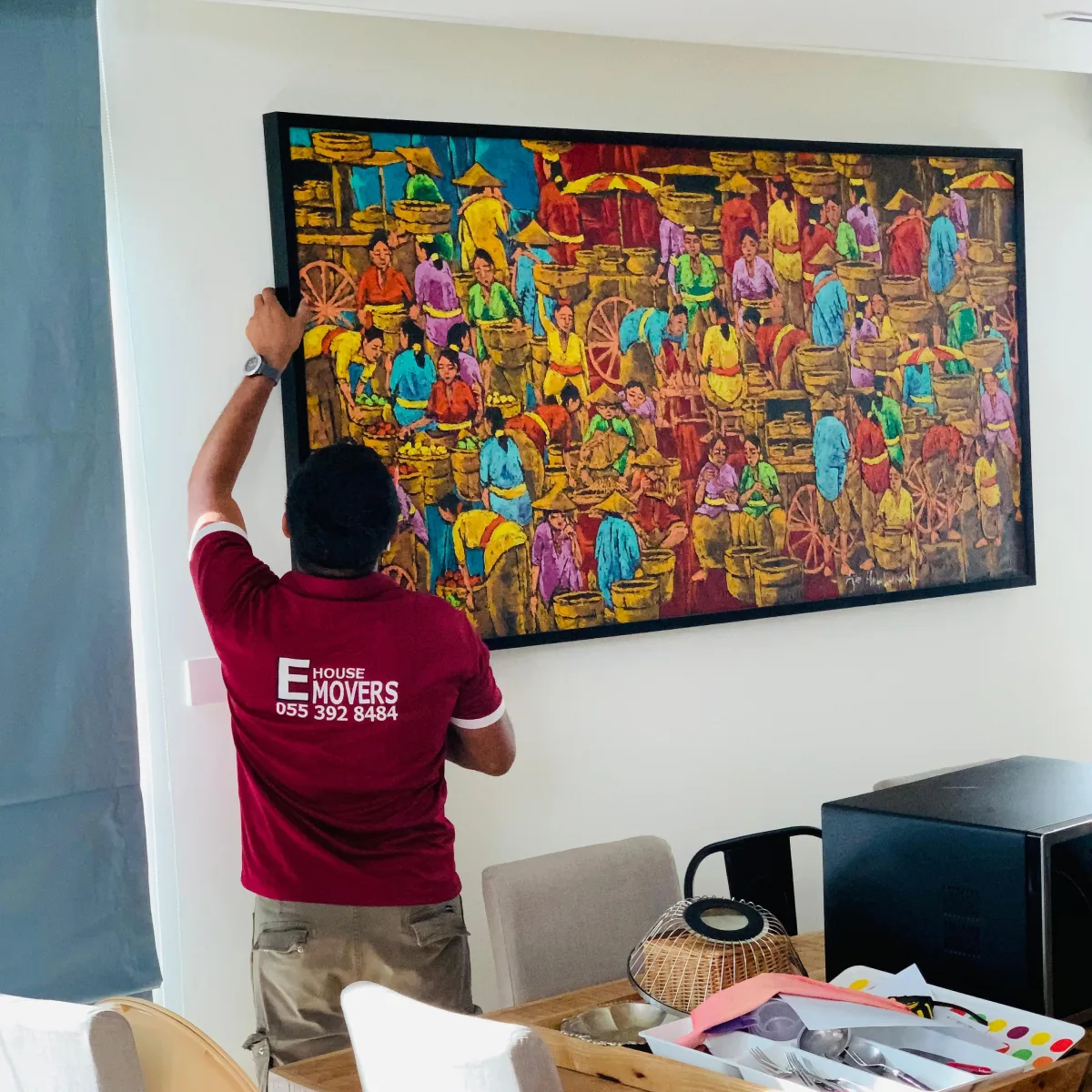 E House Movers mover hanging a large painting