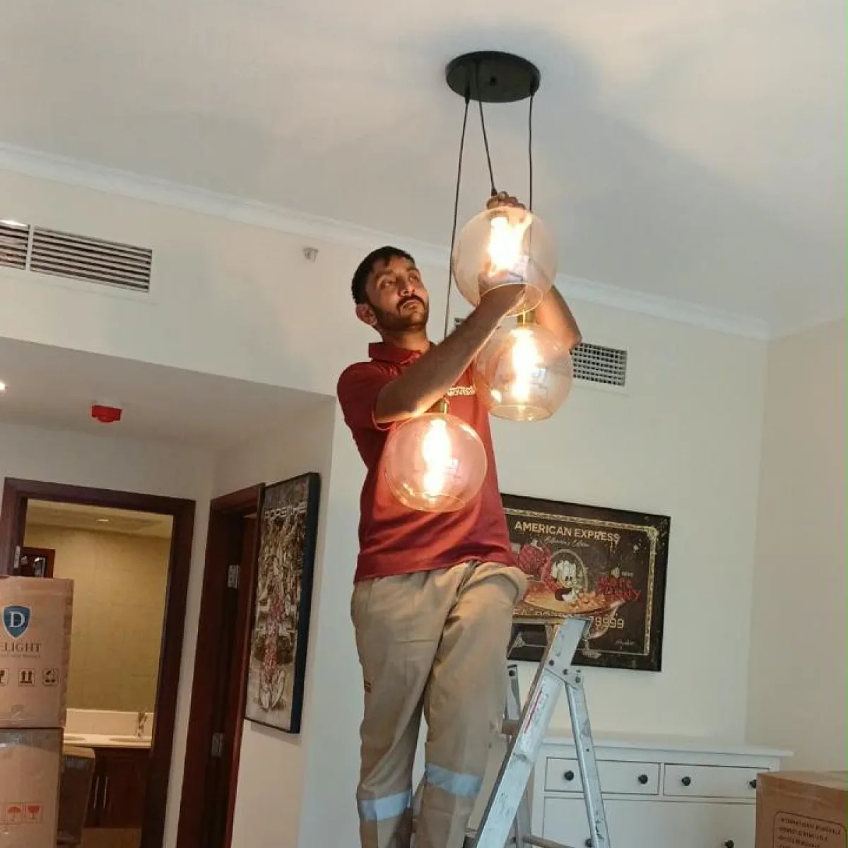 E House Movers mover installing a pendant light in a new home