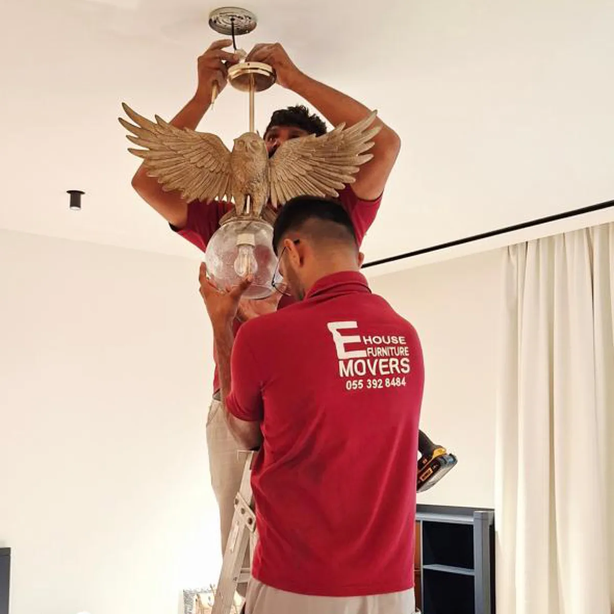 E House Movers crew handling a decorative chandelier in a villa