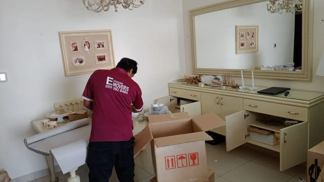 Furniture movers wrapping a wardrobe in moving blankets in Al Quoz